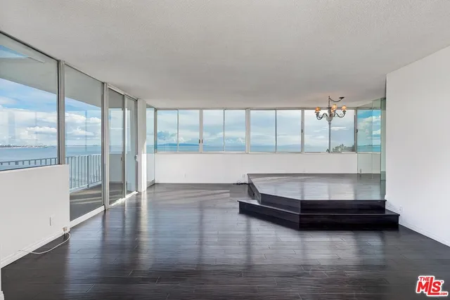 a view of an empty room with wooden floor and a floor to ceiling window