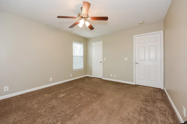 an empty room with a chandelier fan and windows