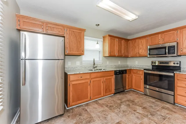 a kitchen with stainless steel appliances granite countertop a refrigerator stove top oven and sink