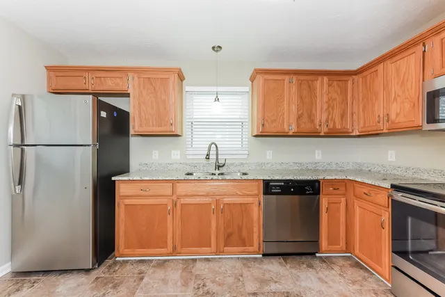 a kitchen with stainless steel appliances granite countertop a refrigerator a stove a sink and dishwasher