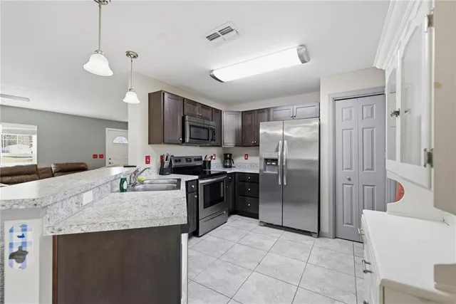 a kitchen with kitchen island a counter top space a sink stainless steel appliances and cabinets