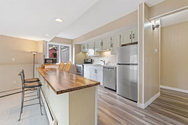 a kitchen with stainless steel appliances granite countertop a refrigerator a stove and a sink with wooden floor