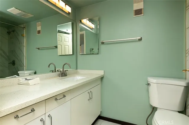a bathroom with a granite countertop sink mirror and toilet