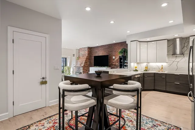 a kitchen with stainless steel appliances granite countertop white cabinets and chairs