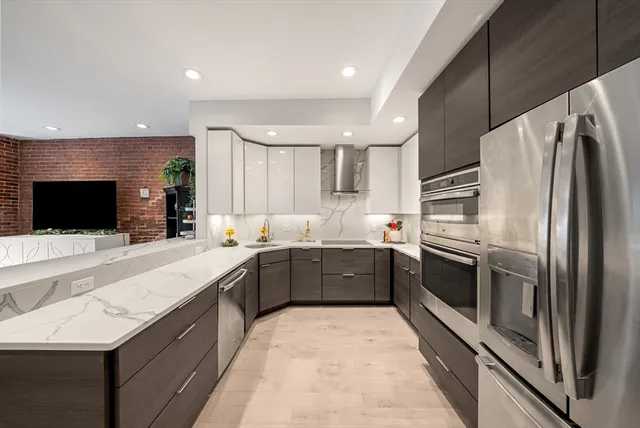 a large kitchen with a large counter top stainless steel appliances and cabinets