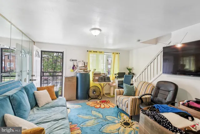 a living room with furniture a flat screen tv and a floor to ceiling window