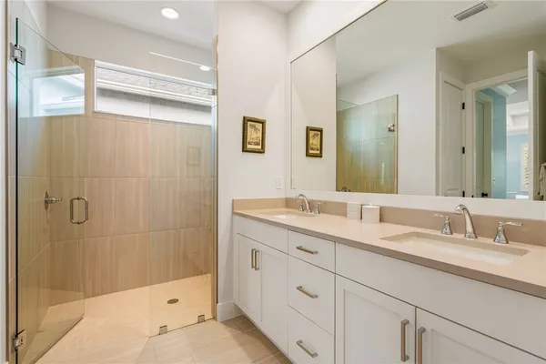 a bathroom with a double vanity sink mirror and shower