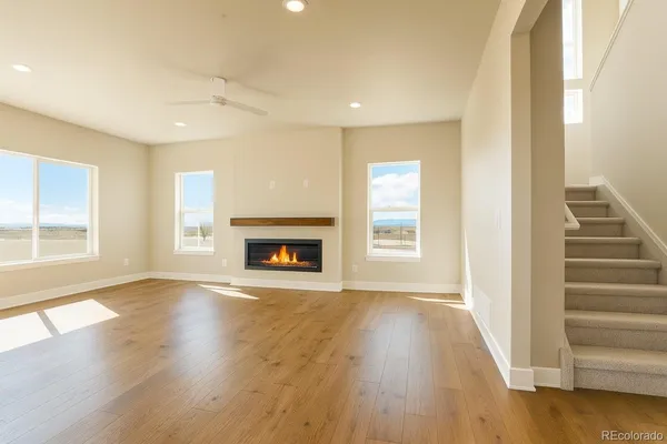 an empty room with wooden floor fireplace and windows