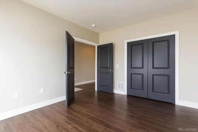 an empty room with wooden floor & closet and windows