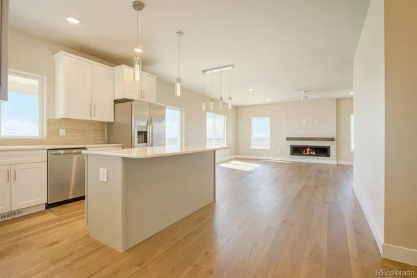 a room with stainless steel appliances kitchen island wooden floors and center island