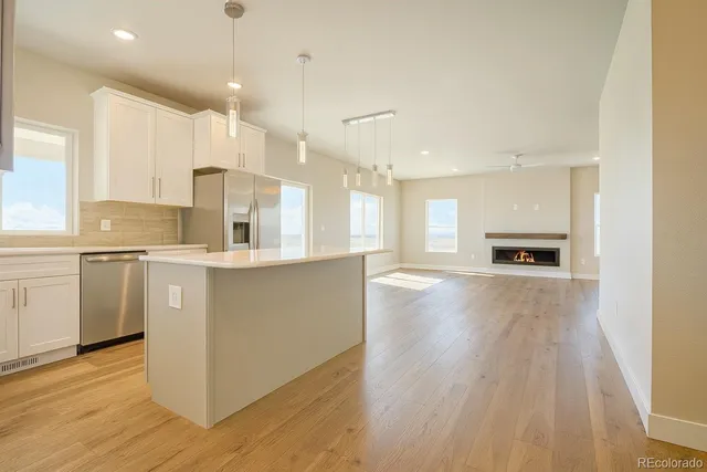 a room with stainless steel appliances kitchen island wooden floors and center island
