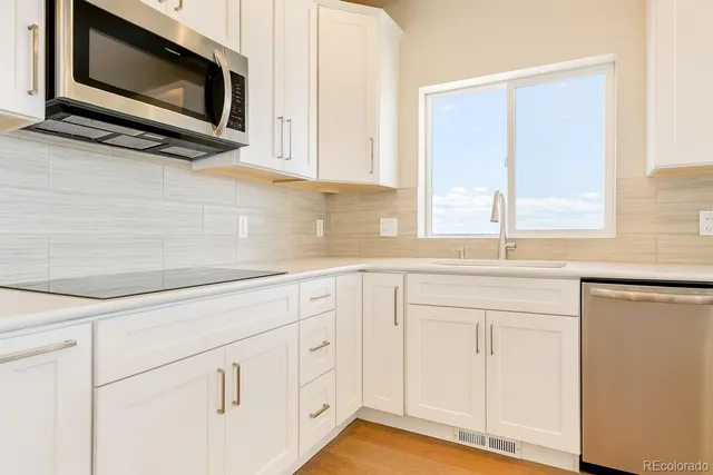 a kitchen with white cabinets appliances and a sink