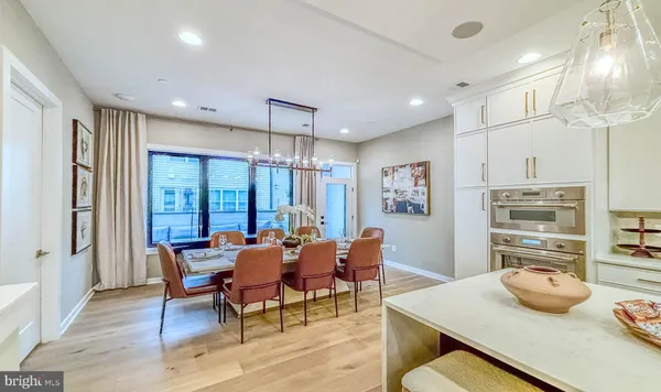 a dining room with stainless steel appliances kitchen island granite countertop a table chairs and a refrigerator