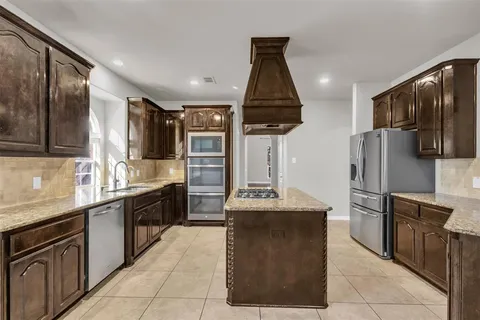 a kitchen with kitchen island stainless steel appliances a sink stove and refrigerator