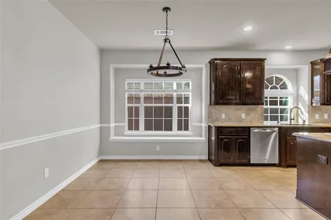 a kitchen with granite countertop a stove a sink a counter space and cabinets