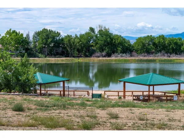 a view of a lake with a table and chairs under an umbrella