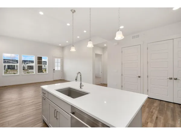 a kitchen with a sink chandelier and wooden floor