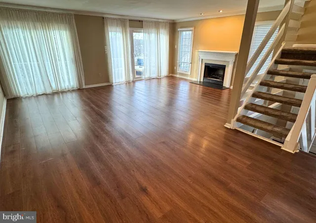 an empty room with wooden floor fireplace and windows
