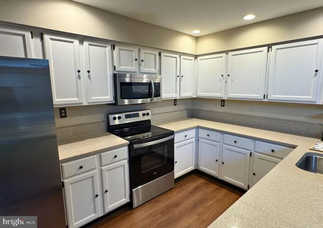 a kitchen with cabinets stainless steel appliances a sink and wooden floor