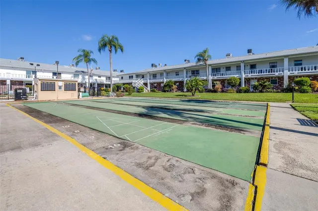 a front view of a building with a garden and trees