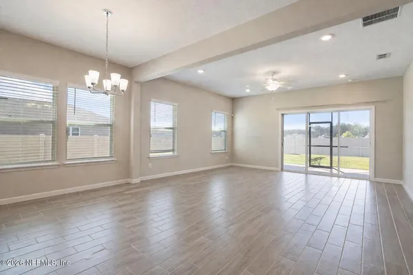 a view of an empty room with chandelier fan and fire place