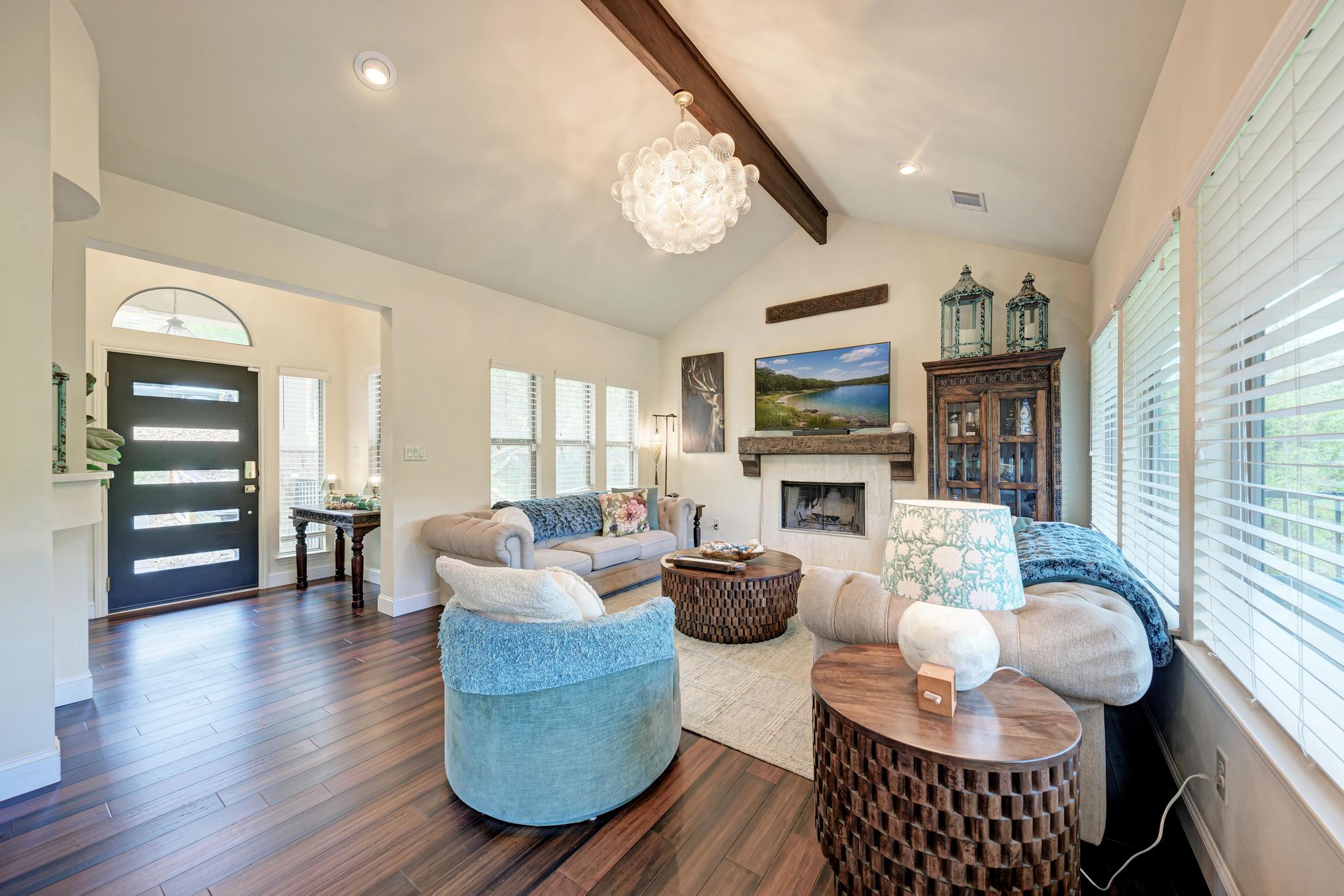 2605 Indian Creek Road Austin, TX 78734 - Photo 4 of 33 Living area featuring wood-finish flooring, vaulted ceiling with exposed beam, and a contemporary chandelier