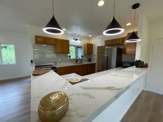 a kitchen with stainless steel appliances granite countertop a sink a stove and a wooden floor