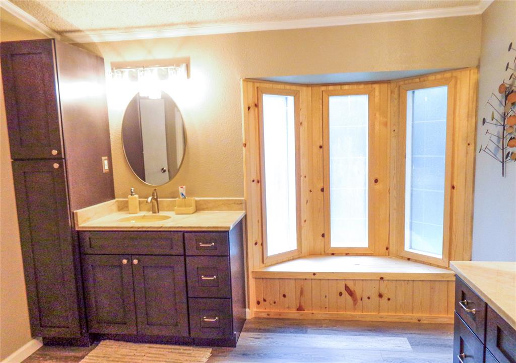 5525 Cedar Oaks Road Grandview, TX 76050 - Photo 16 of 40 Bathroom vanity with a light-colored countertop, an oval mirror, and an adjacent tall storage cabinet