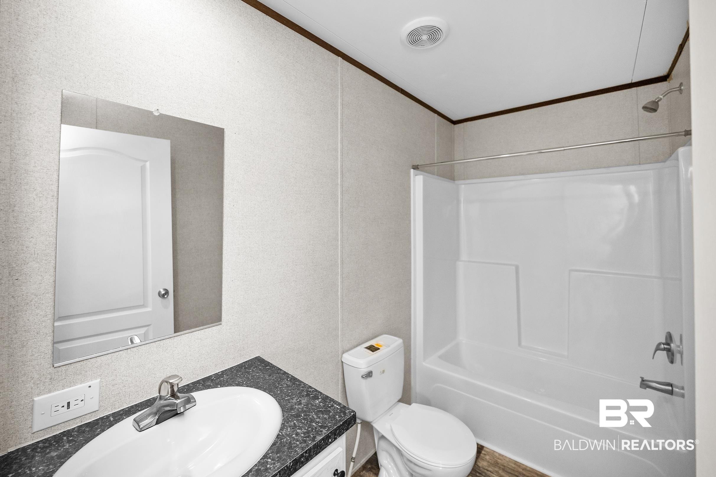 21601 Westside Loop Silverhill, AL 36576 - Photo 27 of 42 Bathroom featuring a white vanity with an integrated sink, dark speckled countertop, and a shower-over-tub combination with a chrome showerhead