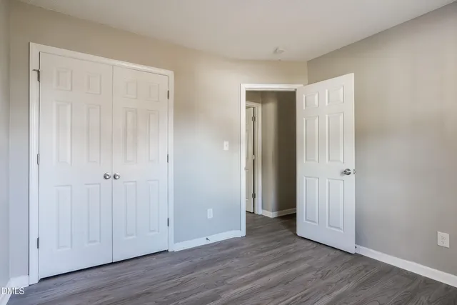 an empty room with wooden floor and closet area