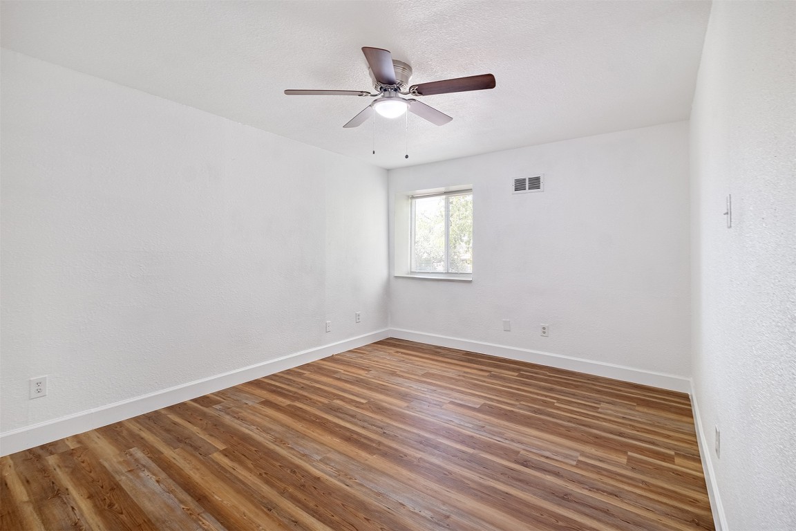 2217 Mission Hill Drive, Unit C Austin, TX 78741 - Photo 14 of 17 a view of an empty room with wooden floor and a ceiling fan