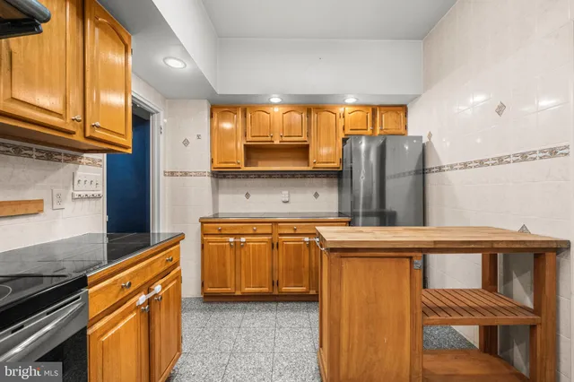 a kitchen with stainless steel appliances granite countertop a refrigerator a stove and a sink with wooden cabinets