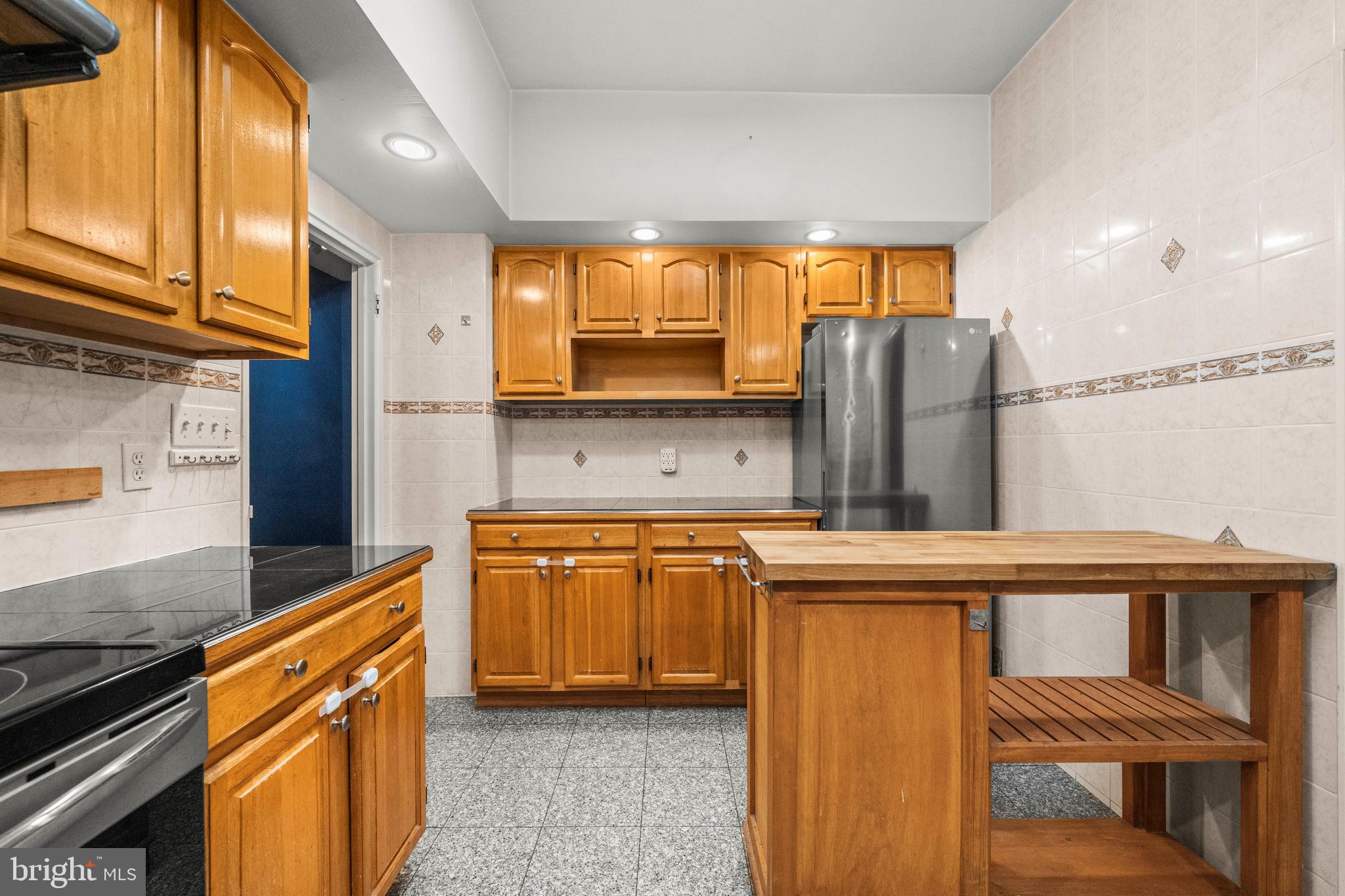 3601 Greenway, Unit 101 Baltimore, MD 21218 - Photo 9 of 32 a kitchen with stainless steel appliances granite countertop a refrigerator a stove and a sink with wooden cabinets
