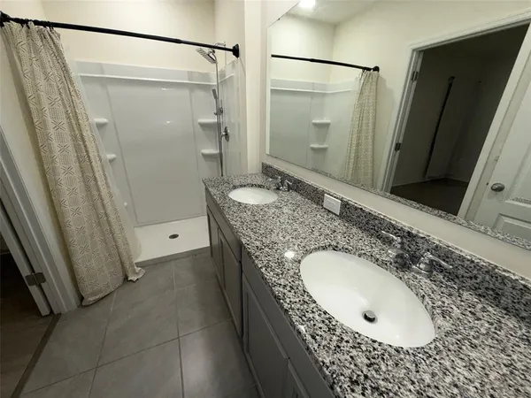 a bathroom with a granite countertop sink a mirror and shower