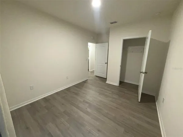 an empty room with wooden floor and mirror
