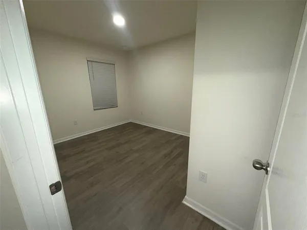 an empty room with wooden floor and window