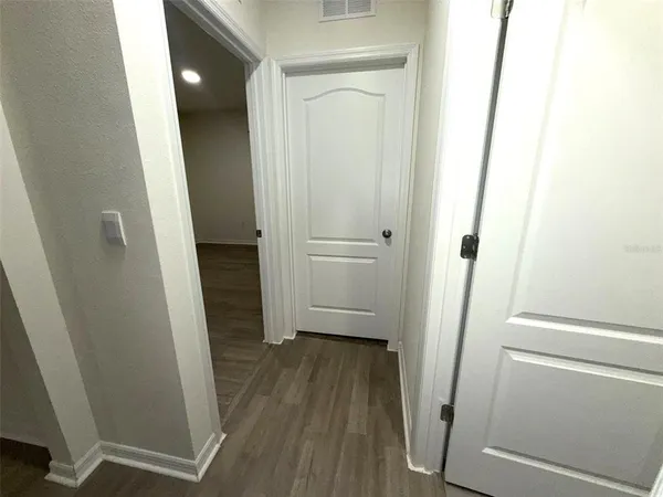 a view of a hallway with wooden floor and closet