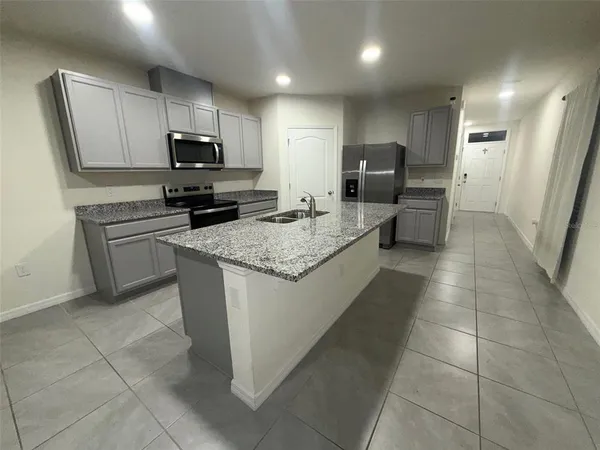 a kitchen with kitchen island granite countertop a sink a counter top space appliances and cabinets