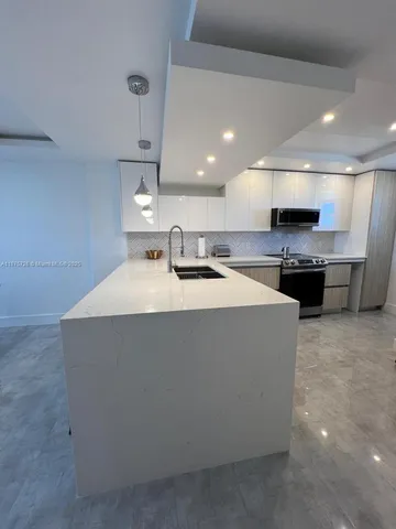 a large kitchen with kitchen island a sink a counter space and stainless steel appliances