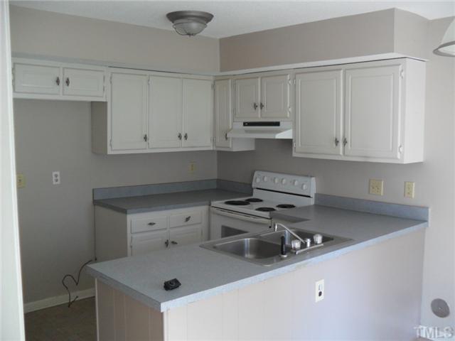 1304 Seaton Road, Unit T2 Durham, NC 27713 - Photo 2 of 8 a kitchen with a sink stove and white cabinets