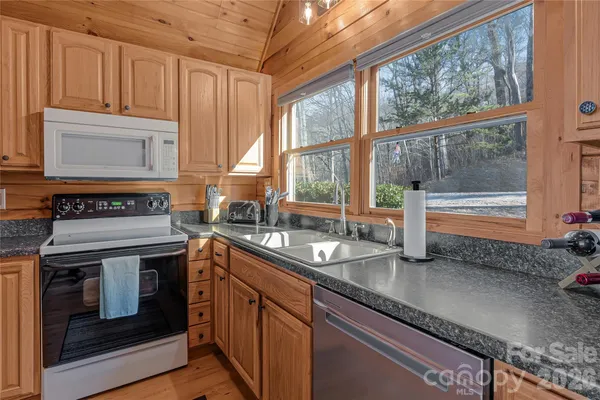 a kitchen with granite countertop a stove a sink and wooden cabinets