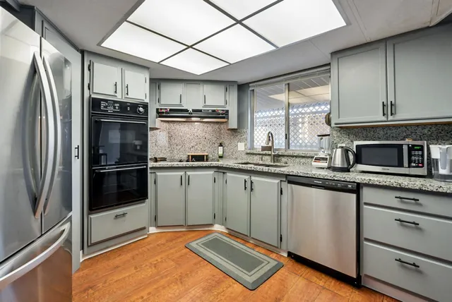 a kitchen with stainless steel appliances granite countertop a refrigerator a stove and a sink