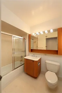 a bathroom with a granite countertop toilet sink and mirror