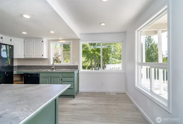 a kitchen with kitchen island granite countertop a stove a sink and a large window