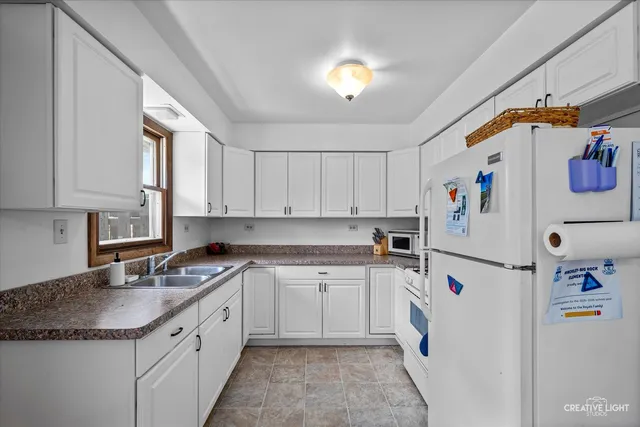 a kitchen with a sink a refrigerator and cabinets