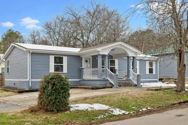 a front view of house with yard and trees in the background