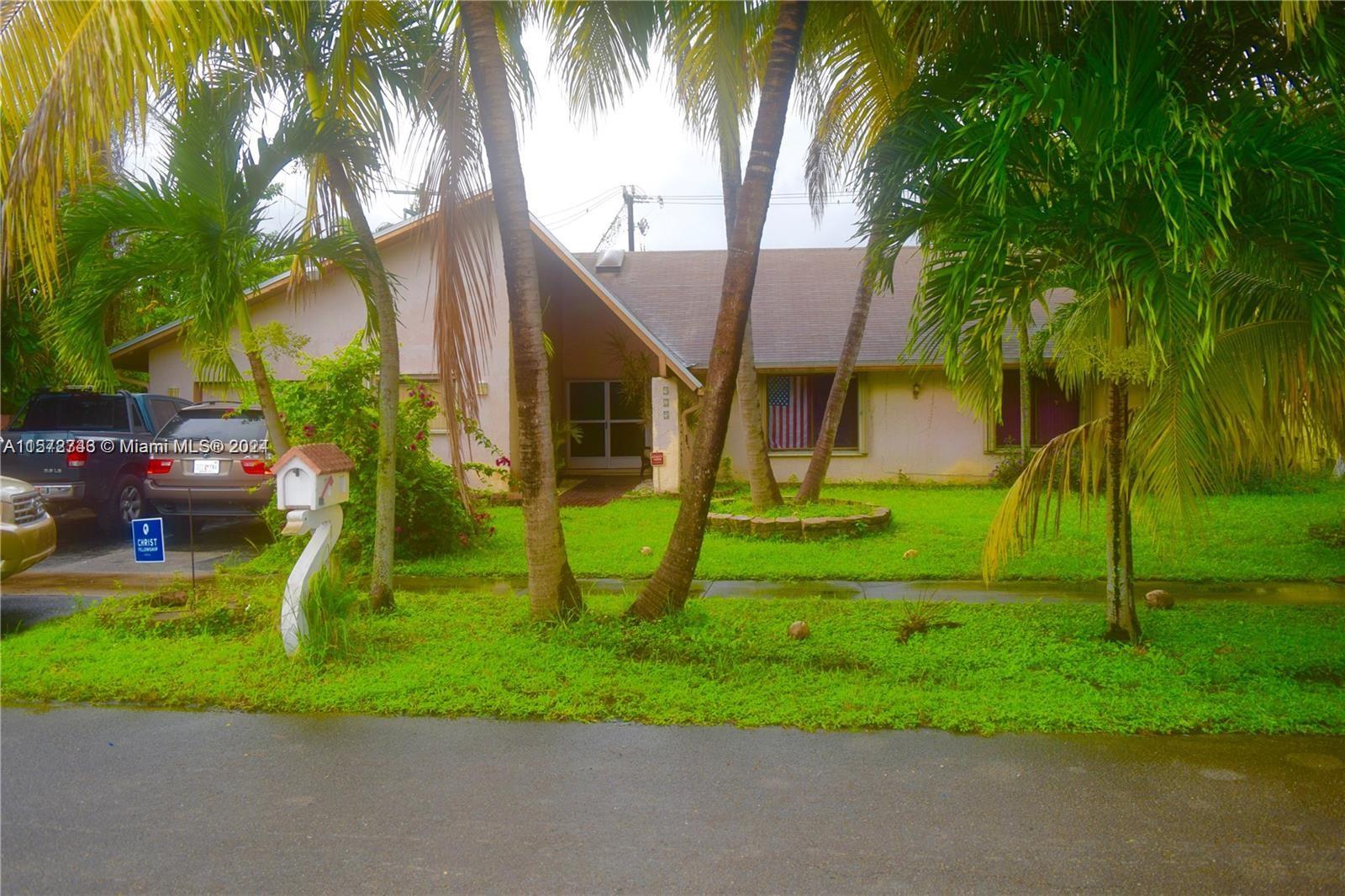 a view of a house with a yard and palm trees
