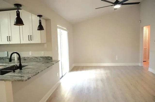 a view of an empty room with a window and wooden floor