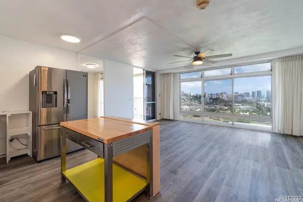 a room with stainless steel appliances kitchen island granite countertop a refrigerator a stove and a wooden floors