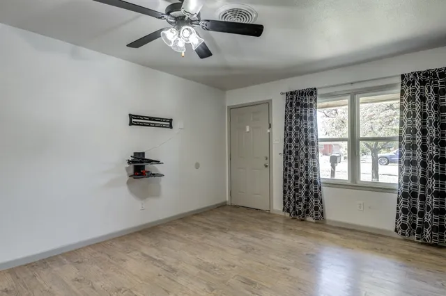 a view of an empty room with a window and wooden floor